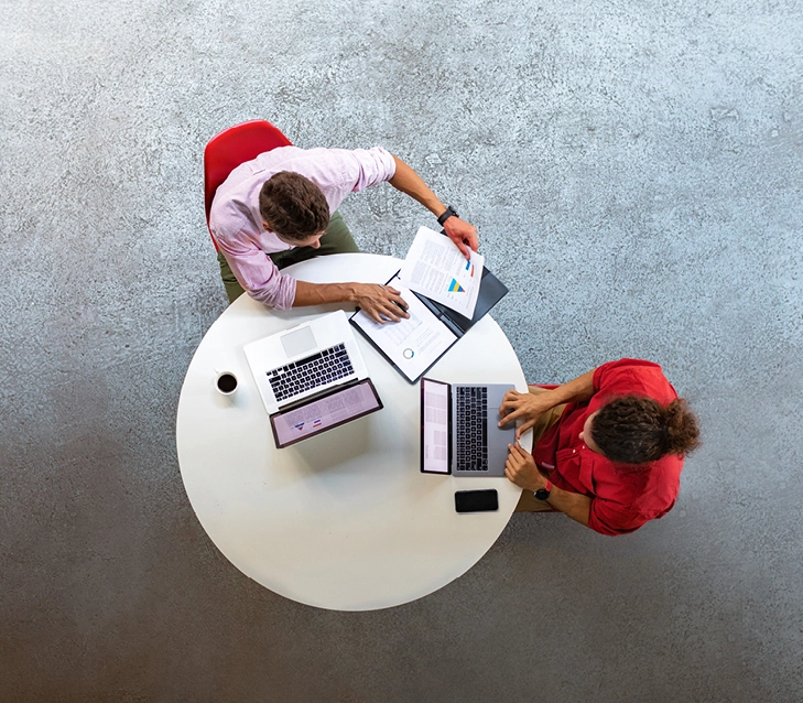 Two people sat at a table looking at documents